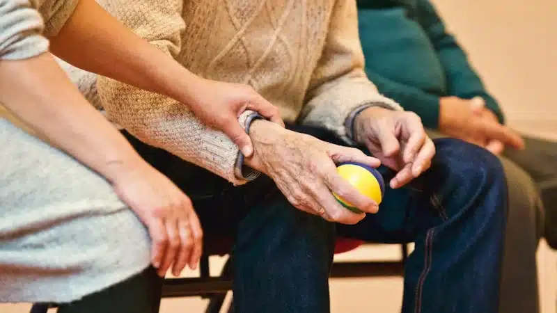 Youth holding hand of older person, laps seen